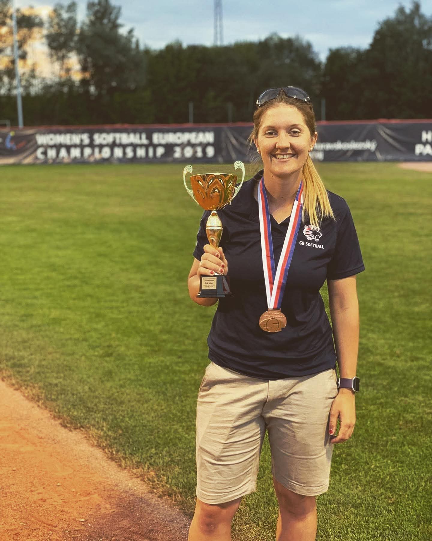 A photo of Kim holding a trophy on a softball field