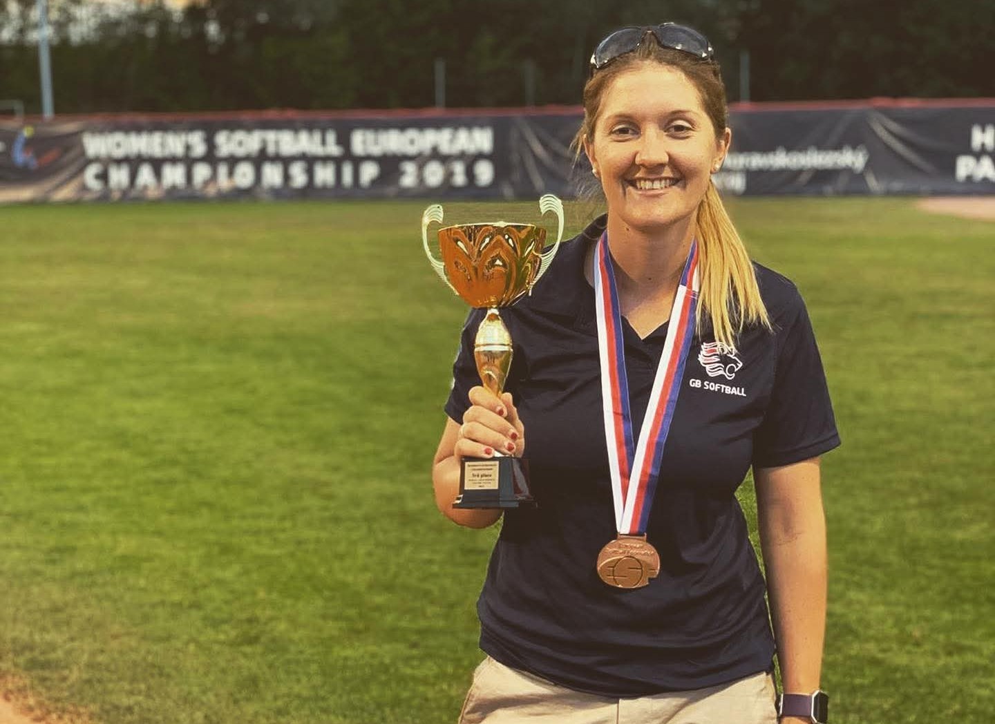 A photo of Kim holding a trophy on a softball field